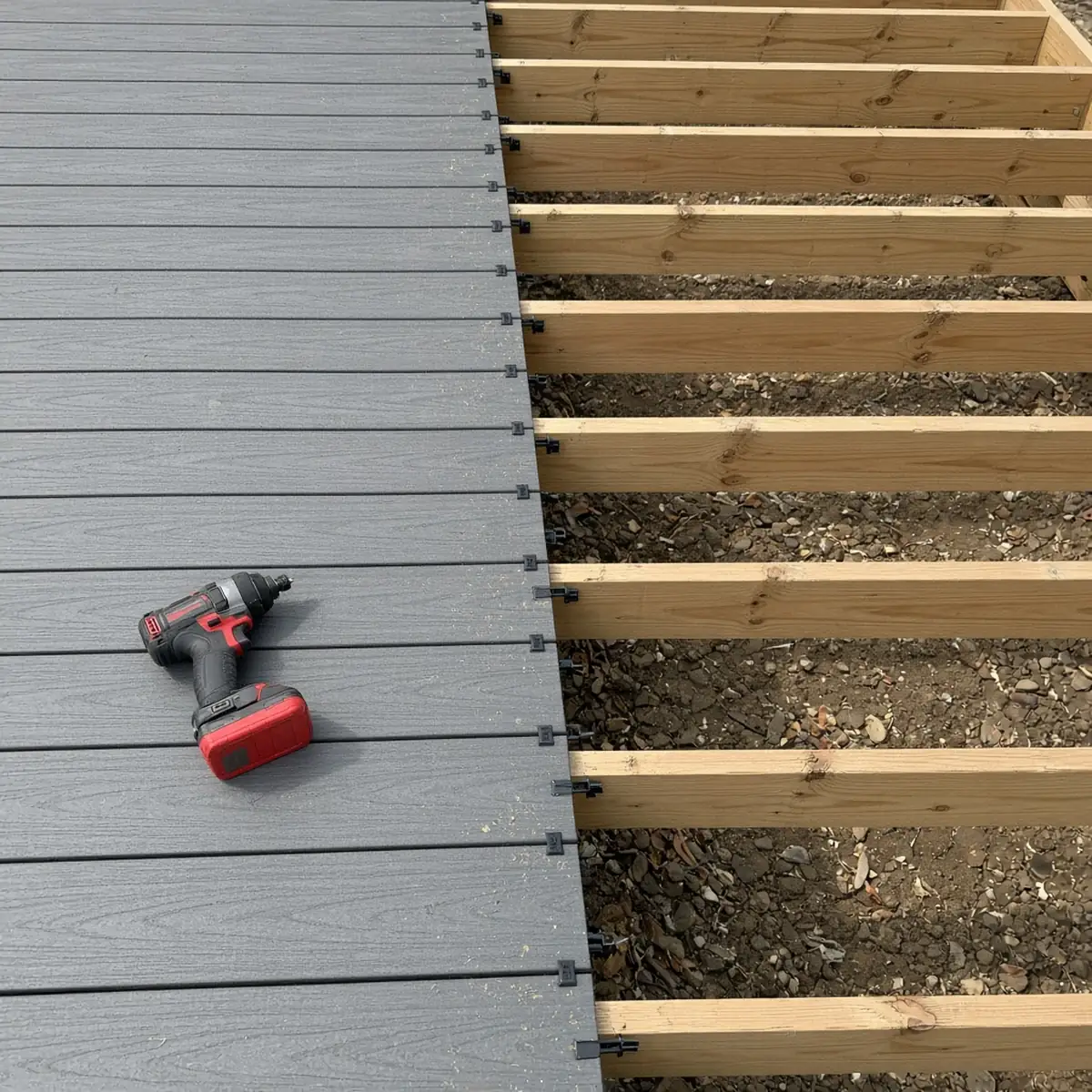Capped composite boards being set with hidden fastener clips on a deck frame